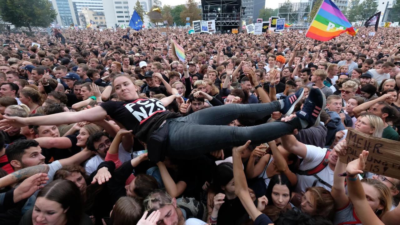 Eine junge Frau wird in einer Zuschauermenge vor dem #wirsindmehr Konzert in Chemnitz hochgetragen Eine junge Frau wird in einer Zuschauermenge vor dem #wirsindmehr Konzert in Chemnitz hochgetragen