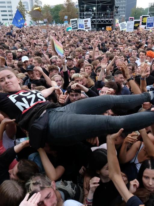 Eine junge Frau wird in einer Zuschauermenge vor dem #wirsindmehr Konzert in Chemnitz hochgetragen