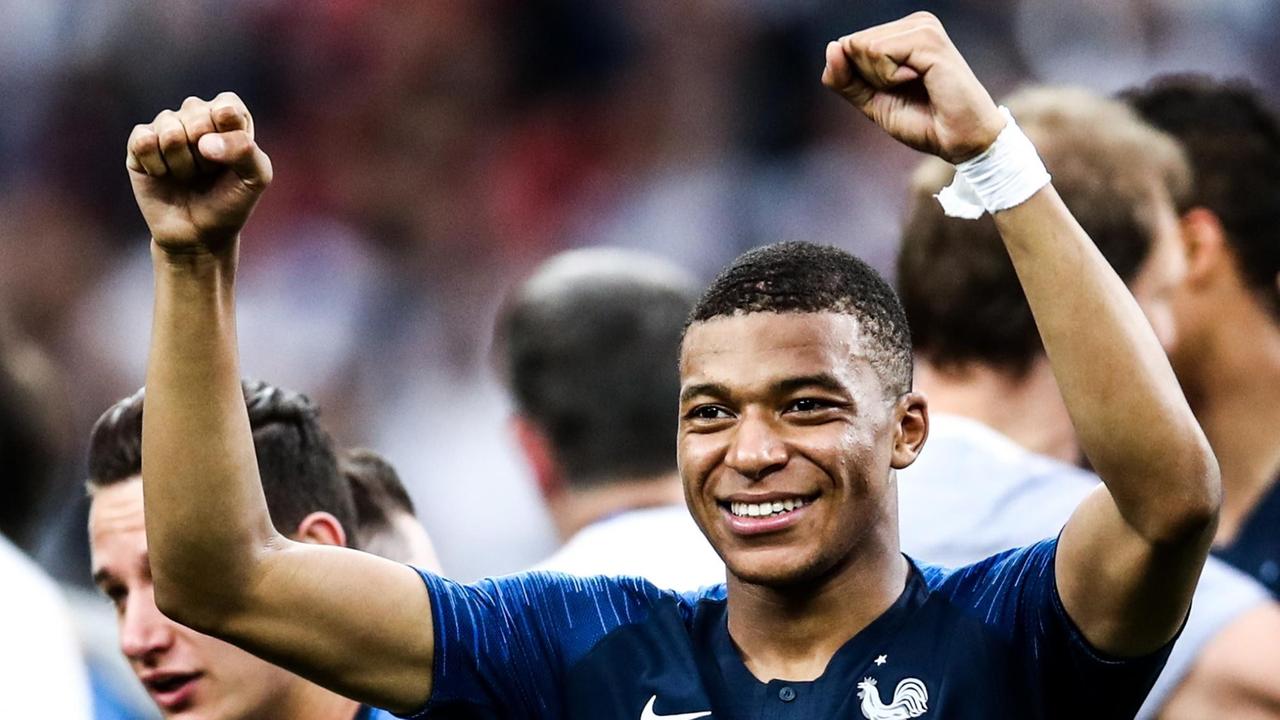 Mbappé lächelt und reckt beide Fäuste in die Höhe. Mbappé lächelt und reckt beide Fäuste in die Höhe.
