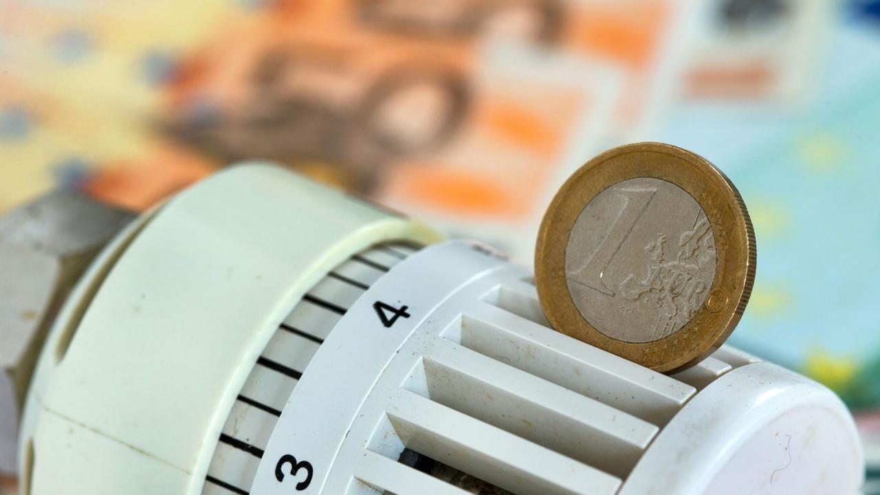 Eine Euromünze steckt in einem Heizungsthermostat.