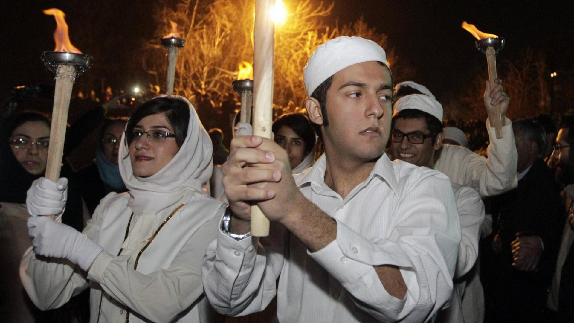 Zoroastrier tragen anlässlich des mittwinterlichen Sadeh-Fests Fackeln durch das iranische Shahriyar. Feuer gilt in der Religion als Medium der Götterverehrung. Zoroastrier tragen anlässlich des mittwinterlichen Sadeh-Fests Fackeln durch das iranische Shahriyar. Feuer gilt in der Religion als Medium der Götterverehrung.
