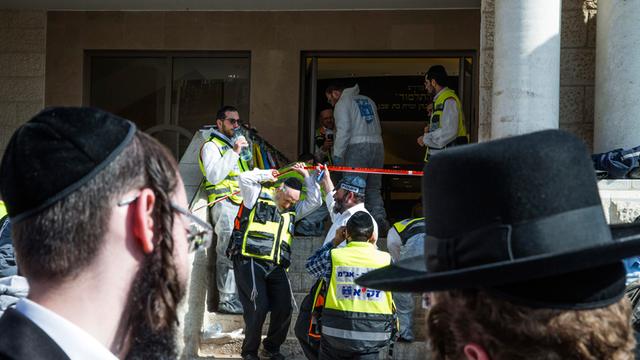 Zwei ultra-orthodoxe Juden blicken auf die Synagoge, in der vier Menschen bei einem Anschlag starben.
