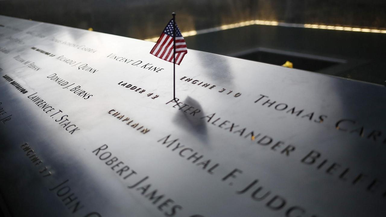Gedenktafel an die Opfer der Anschläge vom 11. September 2001 mit einer US-Flagge.