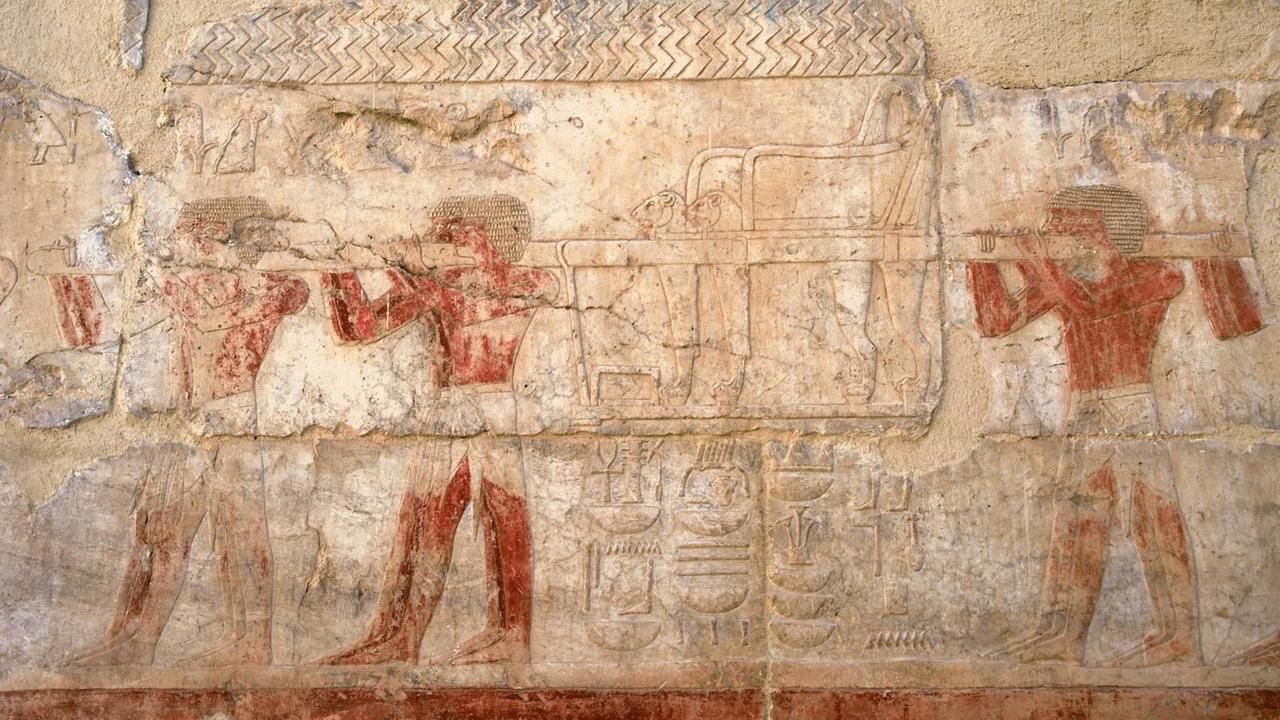 Ein altes ägyptisches Relief aus Luxor im Tempel der Hatschepsut, Königin der 18. Dynastie mit der Darstellung von Sklaven, die einen Thron tragen.  