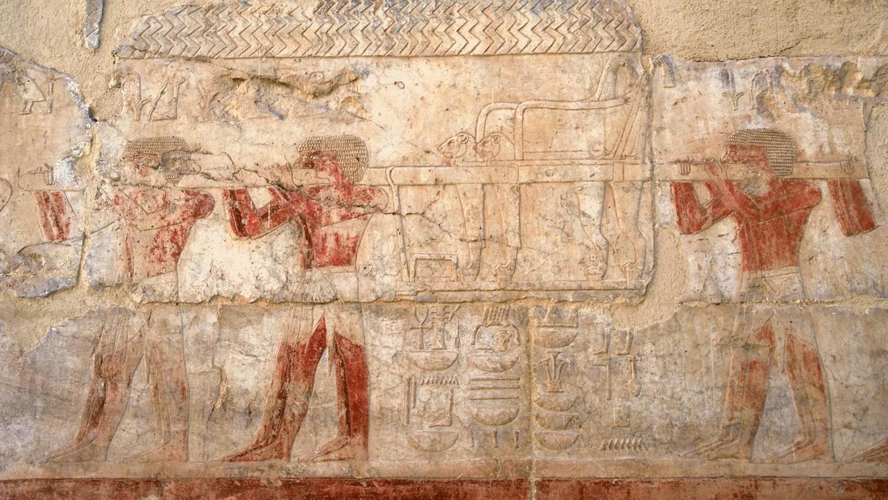 Ein altes ägyptisches Relief aus Luxor im Tempel der Hatschepsut, Königin der 18. Dynastie mit der Darstellung von Sklaven, die einen Thron tragen. Ein altes ägyptisches Relief aus Luxor im Tempel der Hatschepsut, Königin der 18. Dynastie mit der Darstellung von Sklaven, die einen Thron tragen.