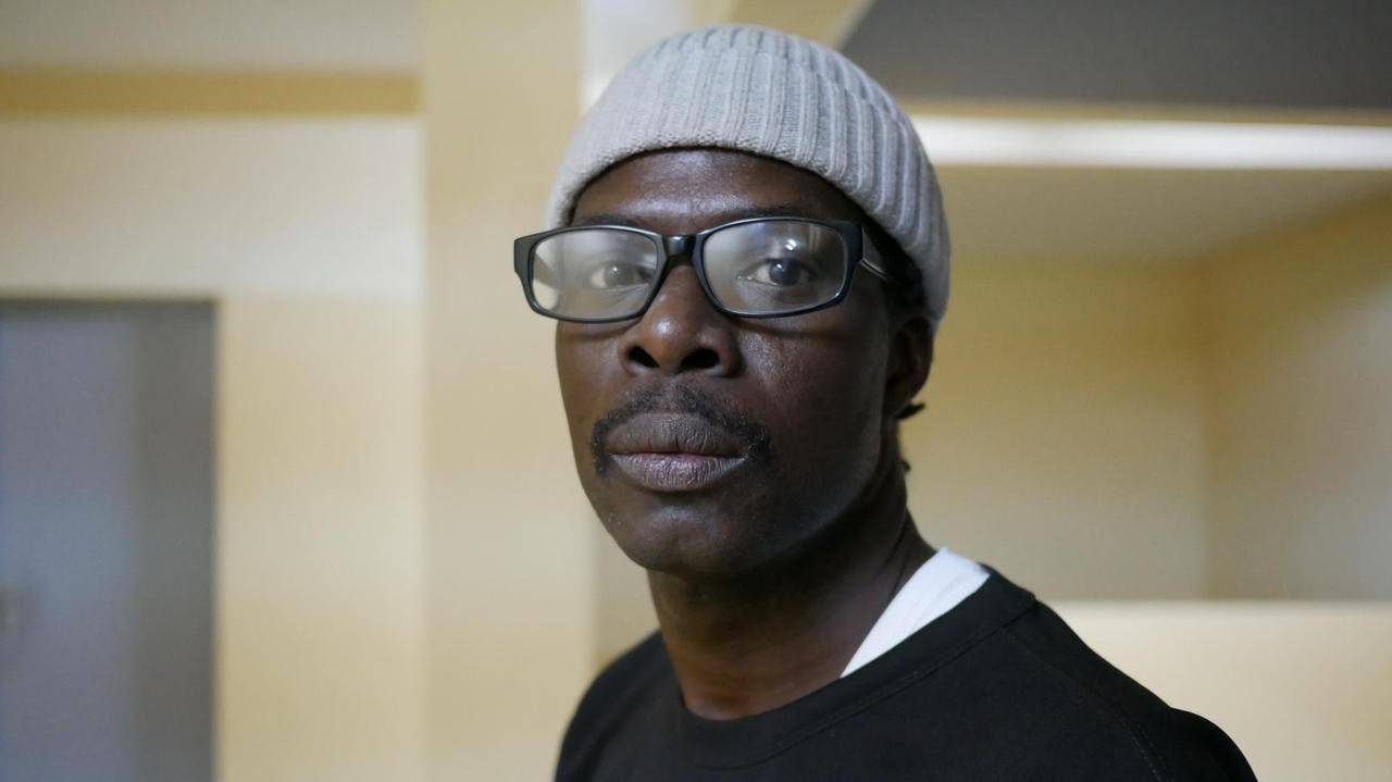 Der Rapper Matador in seinem Kulturzentrum Africulturban. Er trägt eine weiße Mütze und eine Brille. Der Rapper Matador in seinem Kulturzentrum Africulturban. Er trägt eine weiße Mütze und eine Brille.