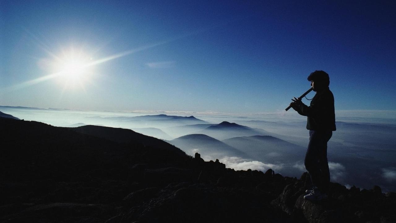 Symbolbild Musik und Natur: Silhouette eines Mannes, der in einer Gebirgslandschaft auf einem Gipfel Flöte spielt. Symbolbild Musik und Natur: Silhouette eines Mannes, der in einer Gebirgslandschaft auf einem Gipfel Flöte spielt.