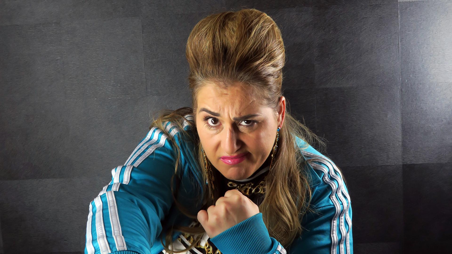 Die Schauspielerin und Kabarettistin Idil Baydar in ihrer Rolle als Jilet Ayse, autoupierter Pony, böser Blick in die Kamera, die Faust geballt (aufgenommen 2015 in Berlin) Die Schauspielerin und Kabarettistin Idil Baydar in ihrer Rolle als Jilet Ayse, autoupierter Pony, böser Blick in die Kamera, die Faust geballt (aufgenommen 2015 in Berlin)