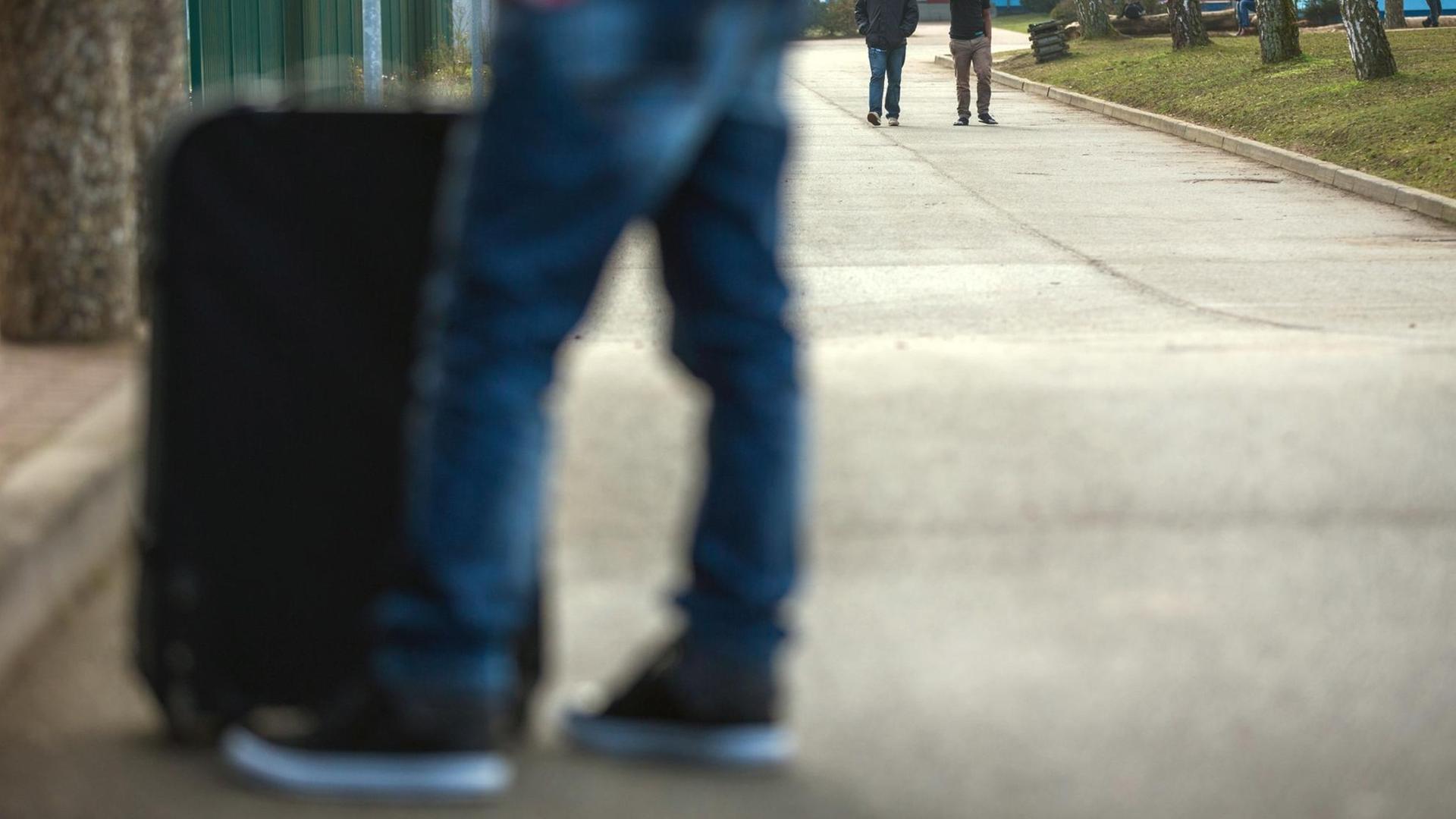 Ein gerade angekommener Asylbewerber steht mit seinem Koffer am Eingang zu Mecklenburg-Vorpommerns zentraler Erstaufnahmeeinrichtung für Flüchtlinge in Horst bei Boizenburg (Mecklenburg-Vorpommern). Ein gerade angekommener Asylbewerber steht mit seinem Koffer am Eingang zu Mecklenburg-Vorpommerns zentraler Erstaufnahmeeinrichtung für Flüchtlinge in Horst bei Boizenburg (Mecklenburg-Vorpommern).