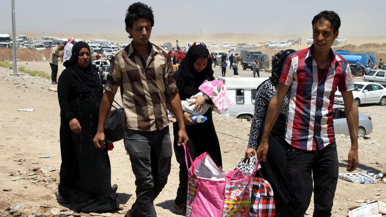 Eine sechsköpfige irakische Familie auf der Flucht vor der Gewalt in Mossul kommt mit einer Tragetasche an einem Checkpoint in Erbil im Nordirak an. Eine sechsköpfige irakische Familie auf der Flucht vor der Gewalt in Mossul kommt mit einer Tragetasche an einem Checkpoint in Erbil im Nordirak an.