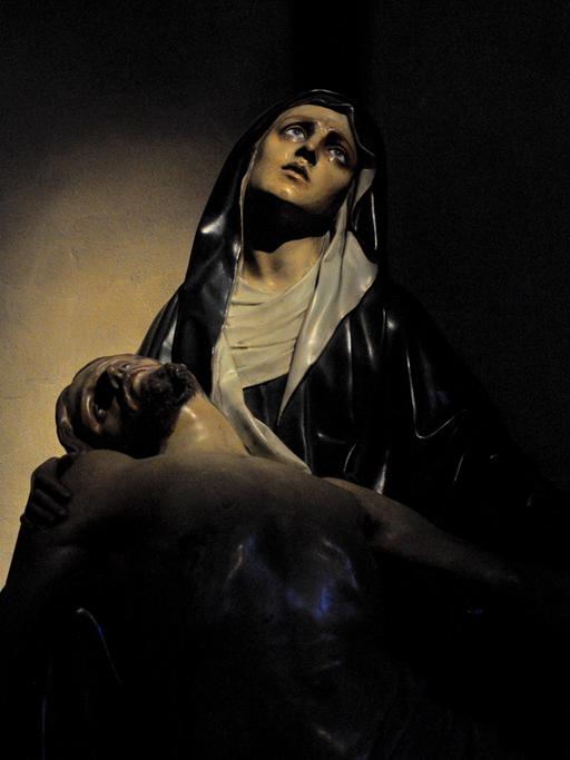Die Figur einer Frau blickt voll Trauer nach oben. Es ist die Mutter Jesu. Es ist eine Darstellung aus einer italienischen Kirche.