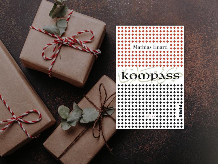 Buchcover von Mathias Enard "Kompass". Im Hintergrund liegen Päckchen mit roten Schleifen.