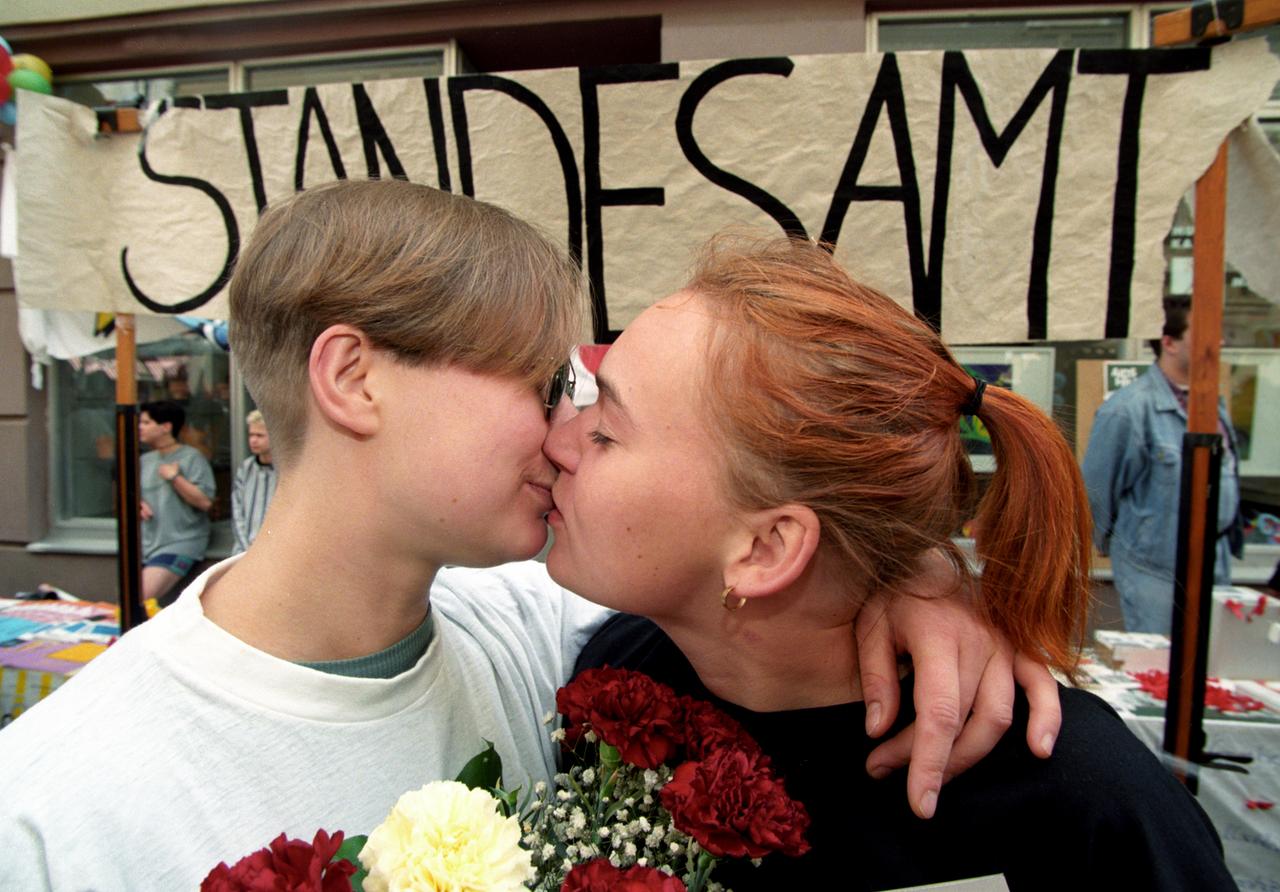Zwei Frauen küssen sich. Dahinter ein Pappschild mit der Aufschrift Standesamt. Zwei Frauen küssen sich. Dahinter ein Pappschild mit der Aufschrift Standesamt.