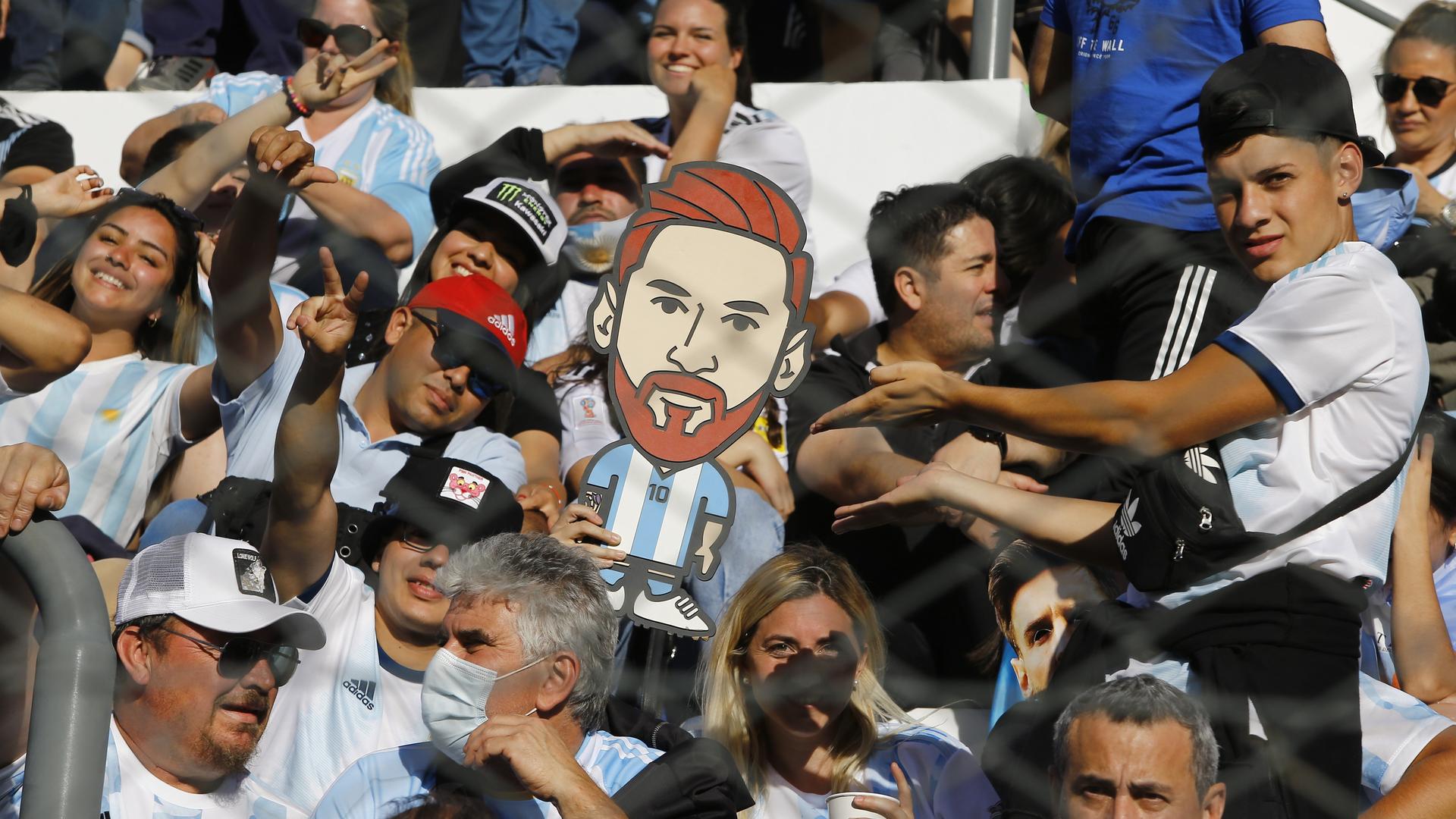 Aficionados al fútbol argentino con la estatua de Messi.