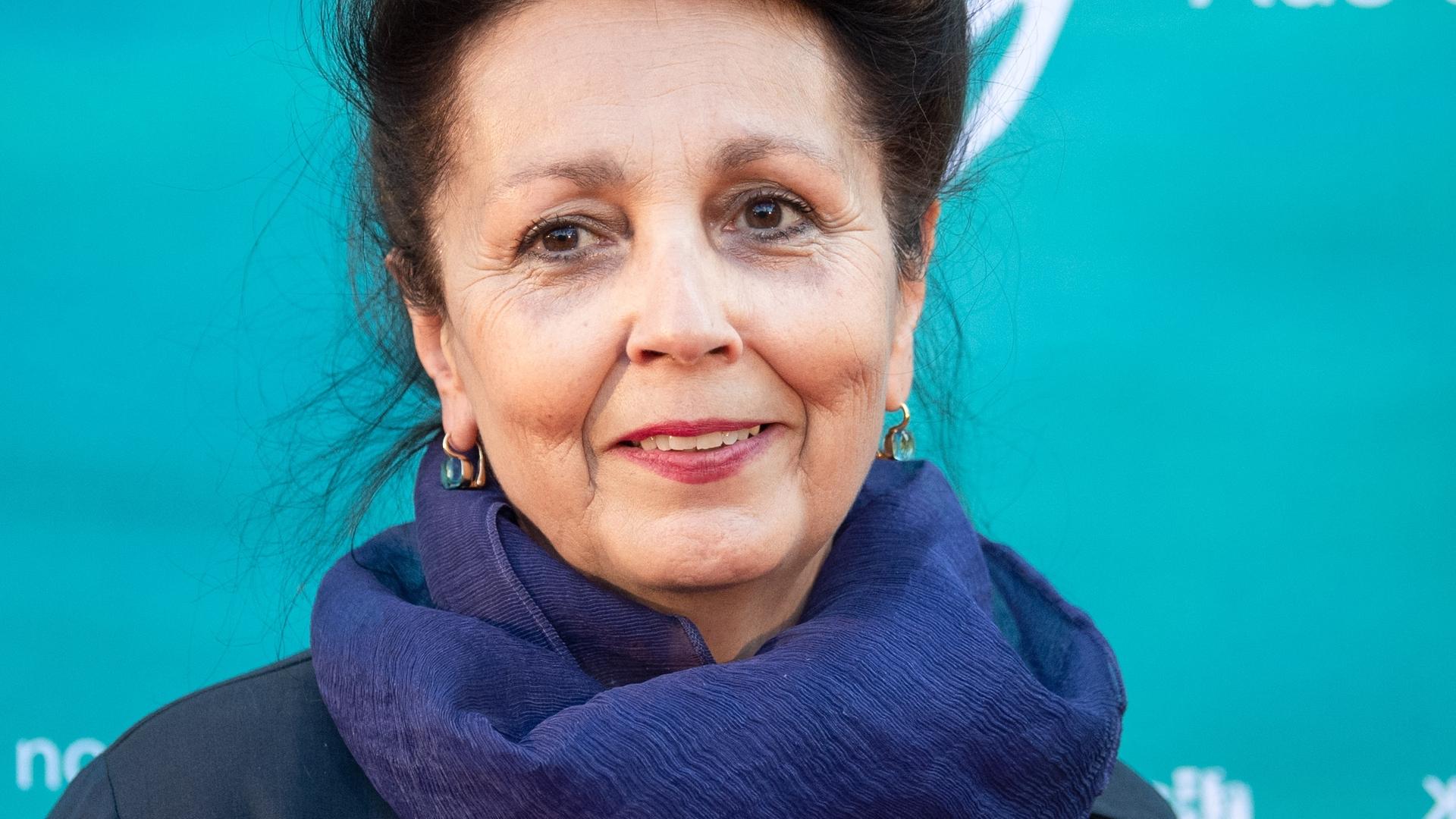 Die Regisseurin Marie Noëlle steht bei der Premiere des Kinofilms "Heinrich Vogeler - Aus dem Leben eines Träumers" vor einem grün-blauen Plakat.