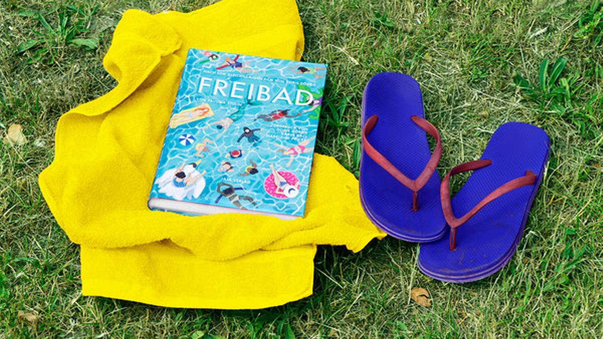 Das Comic "Freibad" liegt auf einer gelben Decke, daneben stehen auf grüner Wiese blaue Flip-Flops. Das Comic "Freibad" liegt auf einer gelben Decke, daneben stehen auf grüner Wiese blaue Flip-Flops.