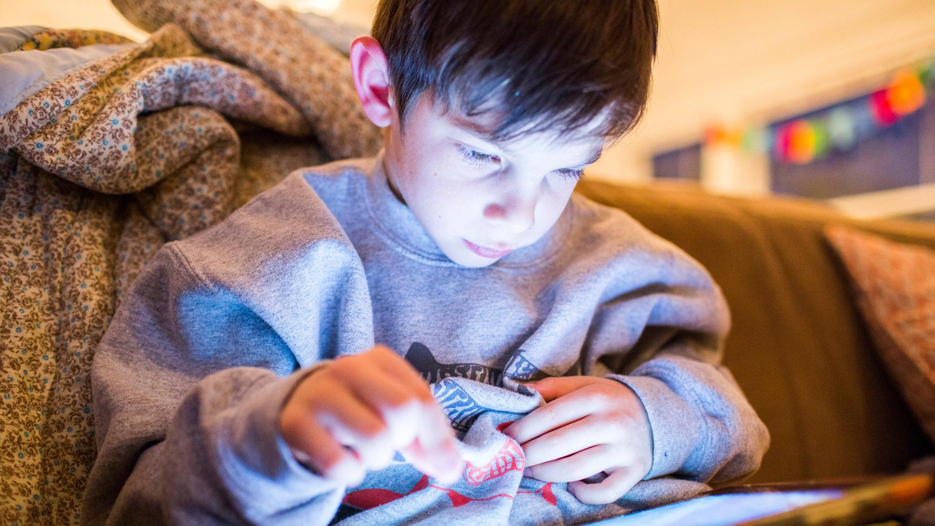 Ein Junge spielt an einem Tablet ein Computerspiele Ein Junge spielt an einem Tablet ein Computerspiele