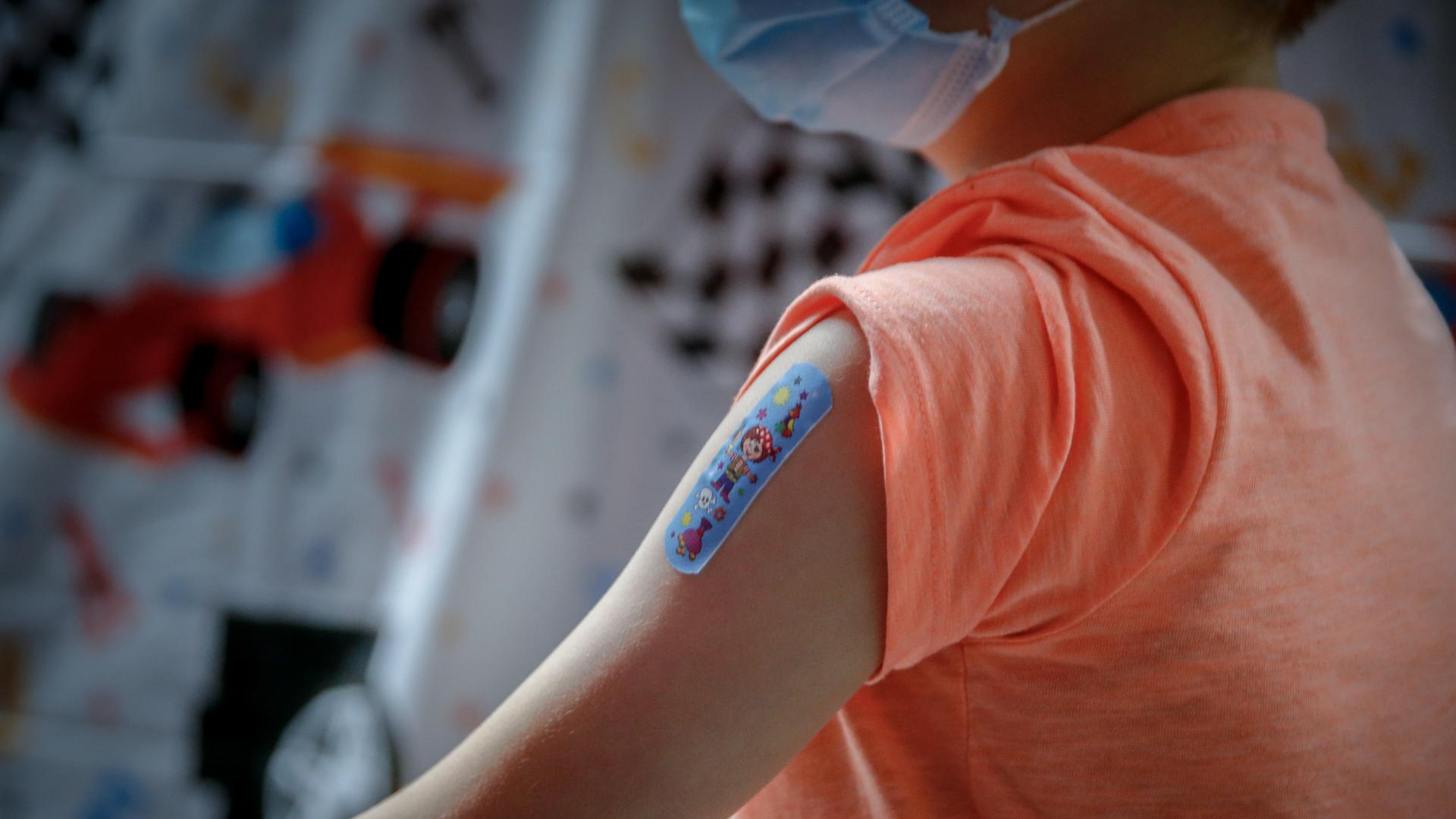 Ein Junge hat ein Pflaster auf seinem Oberarm nach dem er mit dem BioNTech/Pfizer Impfstoff für Kinder geimpft wurde 