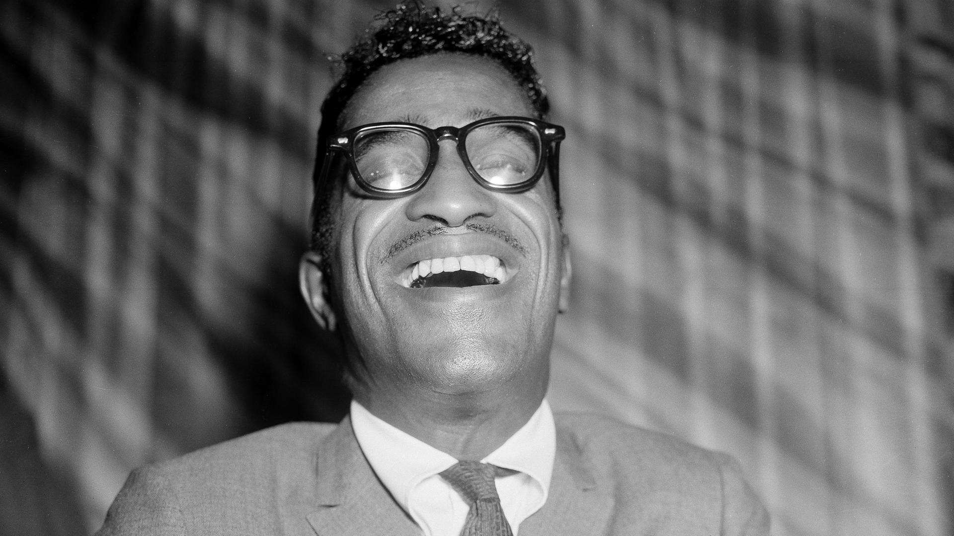 Schwarzweißporträt von Sammy Davis Jr. lachend in einem Londoner Restaurant 1960. Schwarzweißporträt von Sammy Davis Jr. lachend in einem Londoner Restaurant 1960.