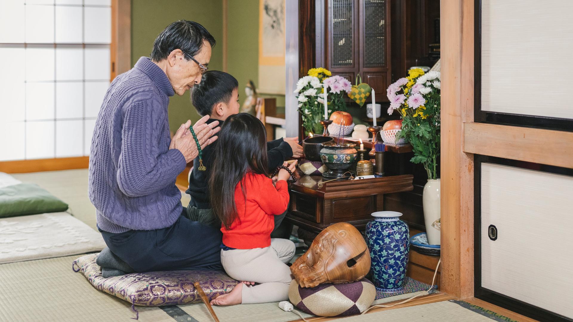 Eine japanische Familie betet vor einem buddhistischem Hausaltar. Eine japanische Familie betet vor einem buddhistischem Hausaltar.