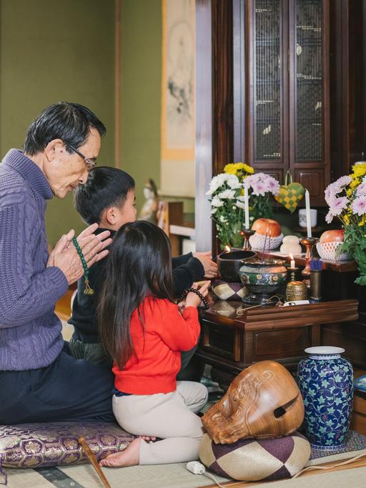 Eine japanische Familie betet vor einem buddhistischem Hausaltar.