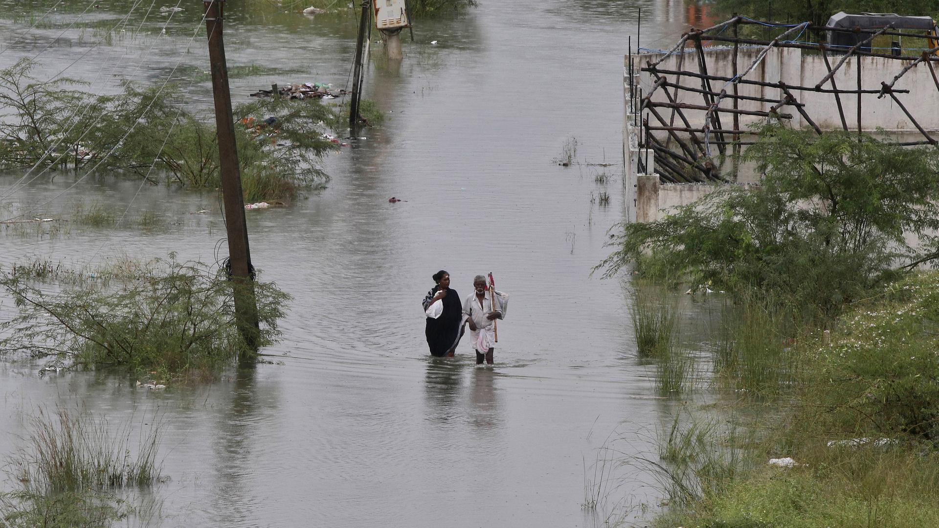 Ein Paar auf einer überfluteten Straße nach einer Flutkatastrophe in Indien 2019 Ein Paar auf einer überfluteten Straße nach einer Flutkatastrophe in Indien 2019