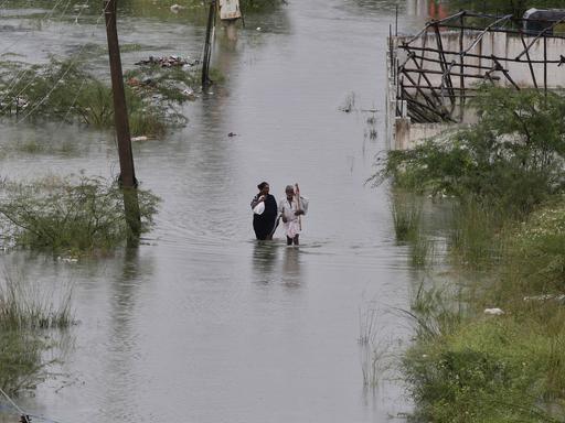 Ein Paar auf einer überfluteten Straße nach einer Flutkatastrophe in Indien 2019