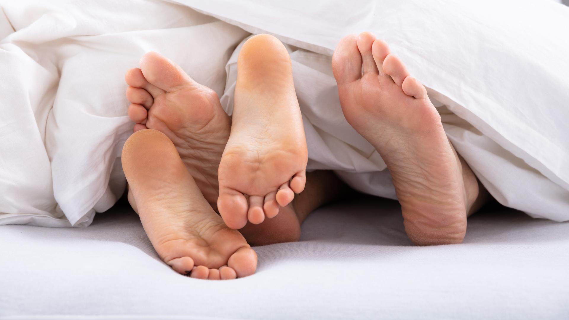 In einem Bett mit weißem Bettzeug liegen zwei Menschen. Sie haben Sex. In einem Bett mit weißem Bettzeug liegen zwei Menschen. Sie haben Sex.