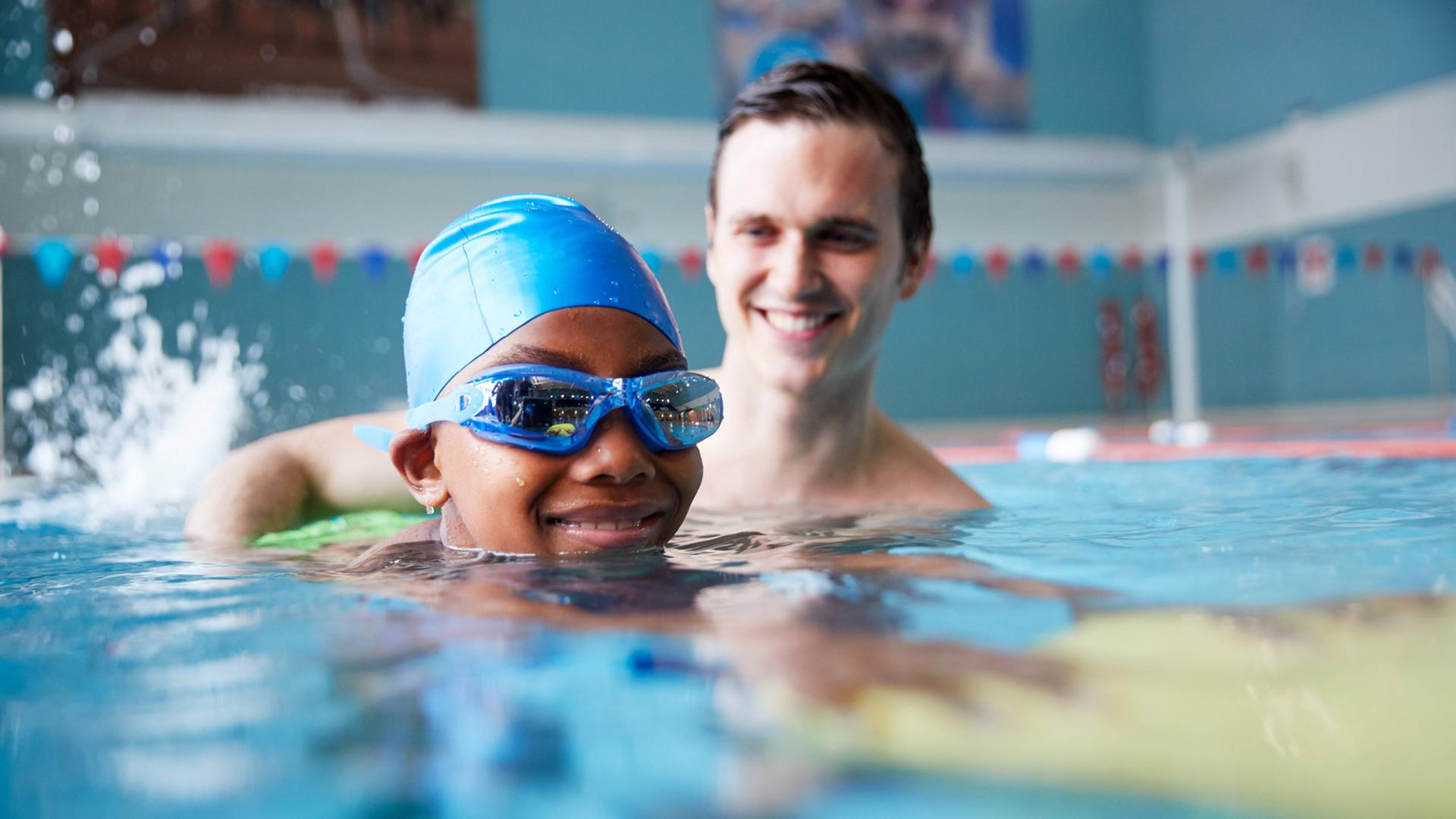 Junger Schwimmtrainer beim Kinderschwimmen Junger Schwimmtrainer beim Kinderschwimmen