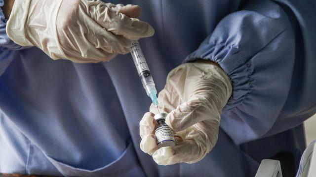 Ein Mitarbeiter eines Gesundheitsdienstes bereitet eine Covid-19-Impfung vor 