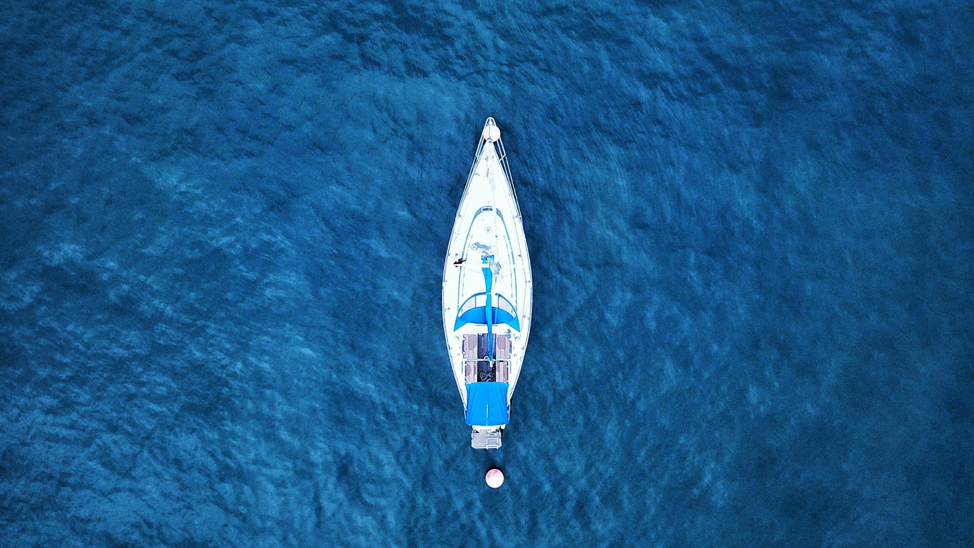 Jähnicke entdeckt eine Yacht, die verlassen auf dem Meer treibt. An Deck: Ein Toter. Zu sehen: Ein Boot auf offener blauer See. Jähnicke entdeckt eine Yacht, die verlassen auf dem Meer treibt. An Deck: Ein Toter. Zu sehen: Ein Boot auf offener blauer See.