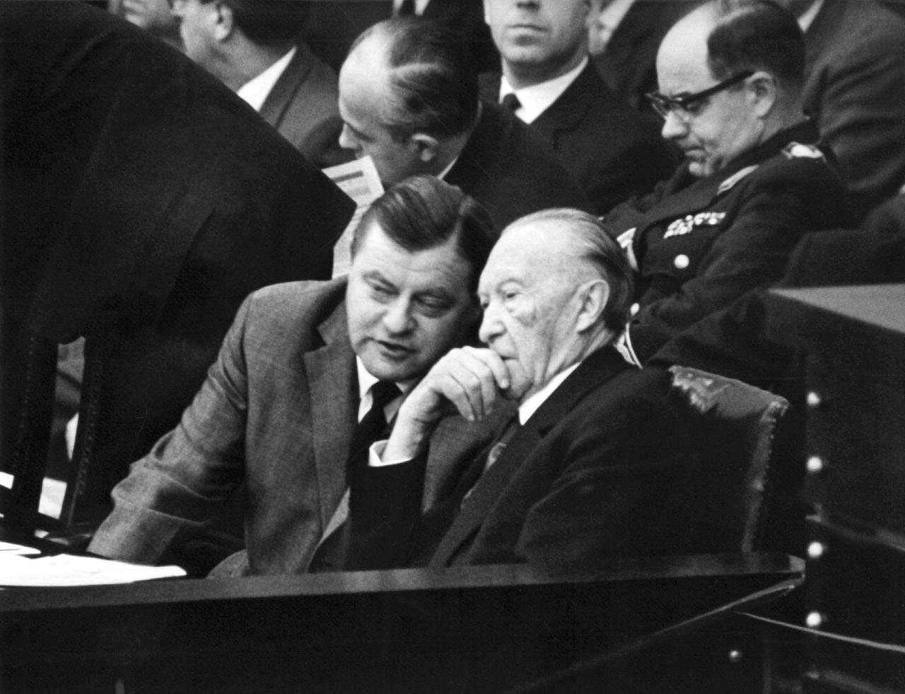 Verteidigungsminister Franz Josef Strauß (l,CSU) im Gespräch mit Bundeskanzler Konrad Adenauer während einer Debatte im Bundestag 1962. 