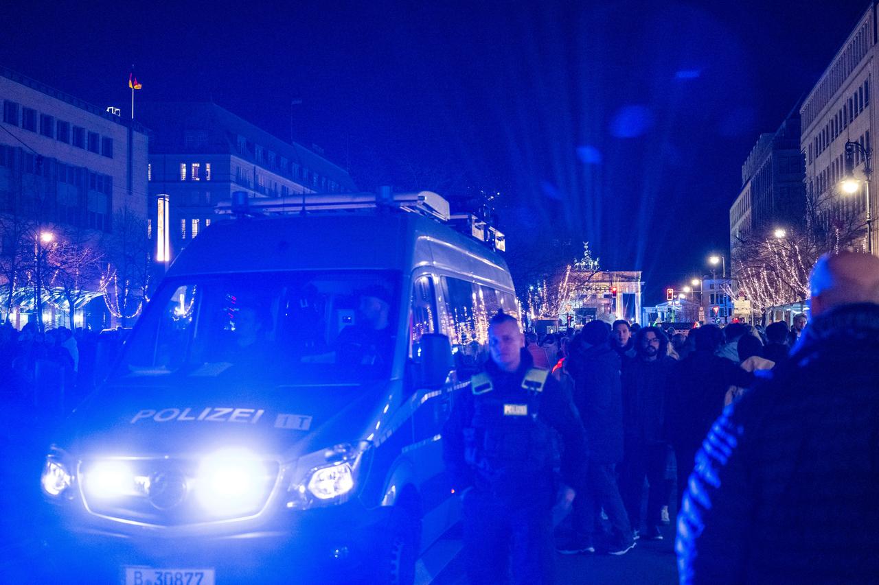 Ein Polizeiauto fährt vor dem Brandenburger Tor mit Blaulicht durch die Menschenmenge. Ein Polizeiauto fährt vor dem Brandenburger Tor mit Blaulicht durch die Menschenmenge.