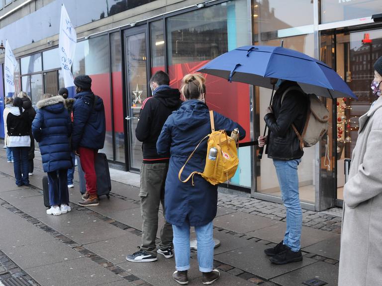 In Kopenhagen stehen Menschen am 30. Dezember in einer Einkaufspassage in einer Schlange, um in einem Testzentrum einen Corona-Schnelltest machen zu lassen.