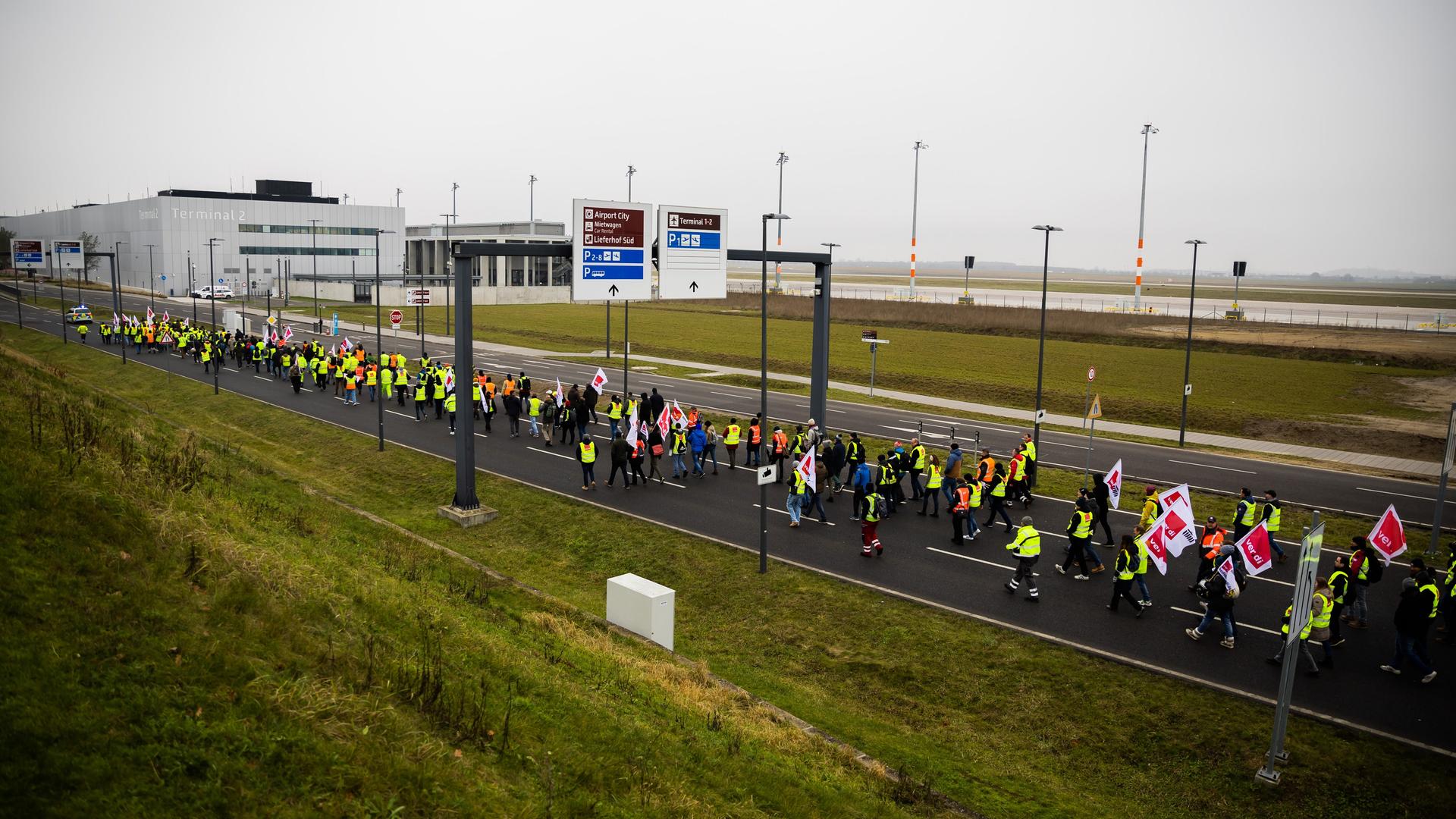 Der Zug einer Demonstration zum Warnstreik am Flughafen Berlin-Brandenburg BER zieht vorbei an Terminal 2 in Richtung Terminal 1. Der Zug einer Demonstration zum Warnstreik am Flughafen Berlin-Brandenburg BER zieht vorbei an Terminal 2 in Richtung Terminal 1.