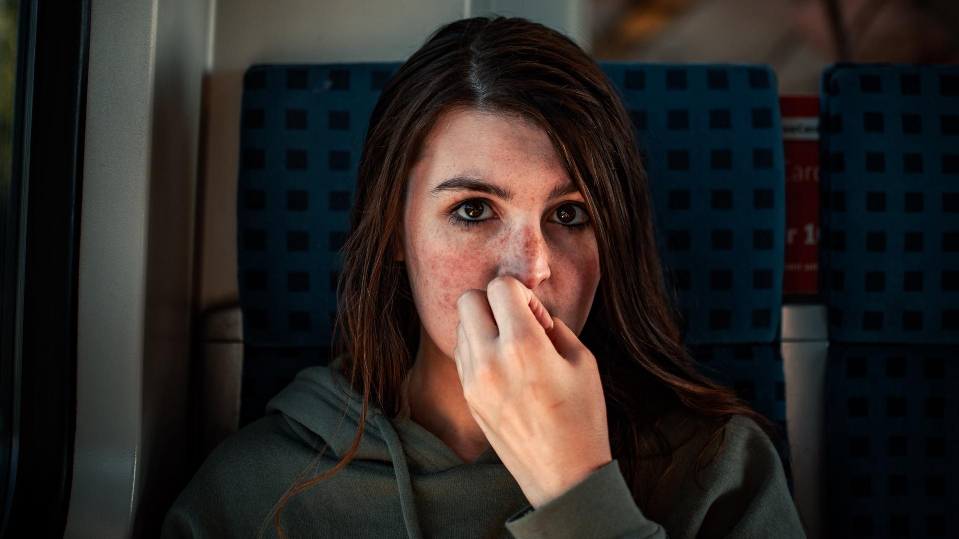 Eine junge Frau kaut auf ihren Nägeln und schaut dabei mit unsicherem Blick in die Kamera. Eine junge Frau kaut auf ihren Nägeln und schaut dabei mit unsicherem Blick in die Kamera.