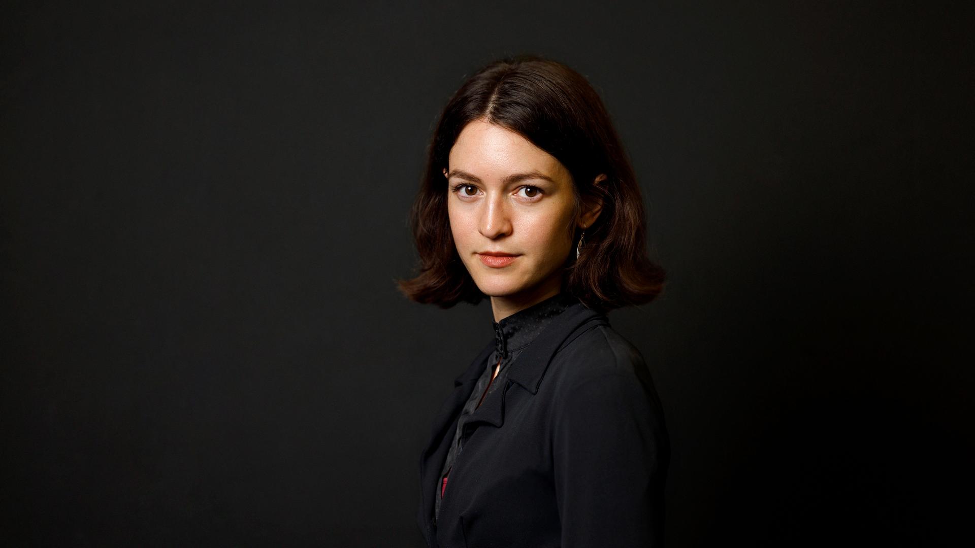 Julia Ebner posiert vor einem schwarzen Hintergrund für ein Porträt.