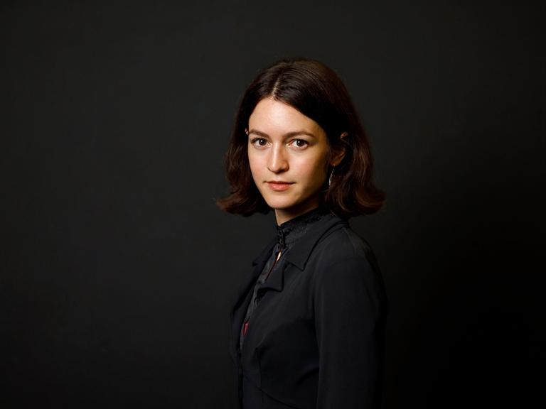 Julia Ebner posiert vor einem schwarzen Hintergrund für ein Porträt.