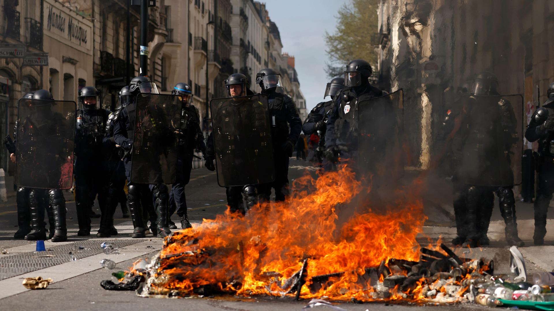 Polizisten stehen vor einem Feuer auf einer Straße in Nantes in Frankreich.