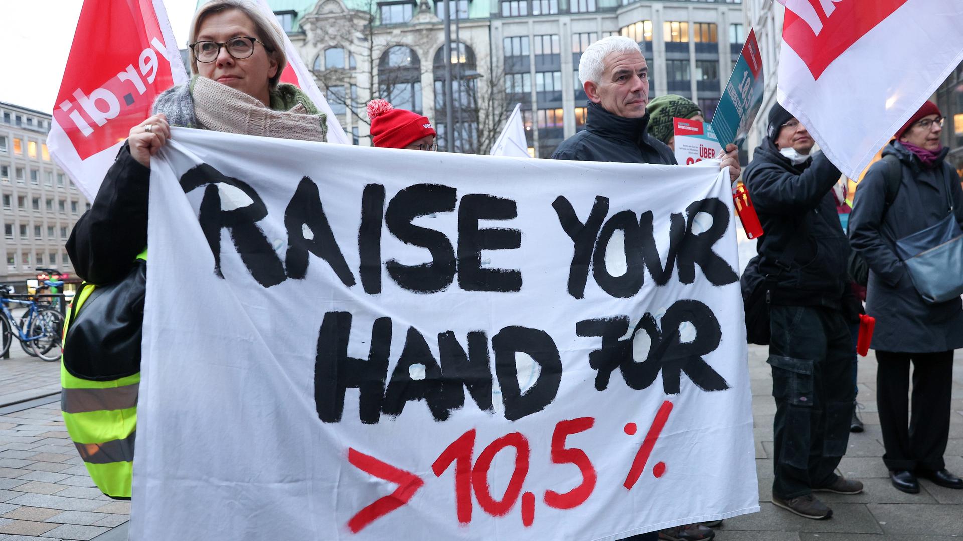 Beschäftigte im öffentlichen Dienst demonstrieren im Rahmen einer Unterschriftenübergabe an Hamburgs Finanzsenator vor der Finanzbehörde auf dem Gänsemarkt und halten ein Transparent mit der Aufschrift "Raise your Hand for > 10,5 %". Beschäftigte im öffentlichen Dienst demonstrieren im Rahmen einer Unterschriftenübergabe an Hamburgs Finanzsenator vor der Finanzbehörde auf dem Gänsemarkt und halten ein Transparent mit der Aufschrift "Raise your Hand for > 10,5 %".