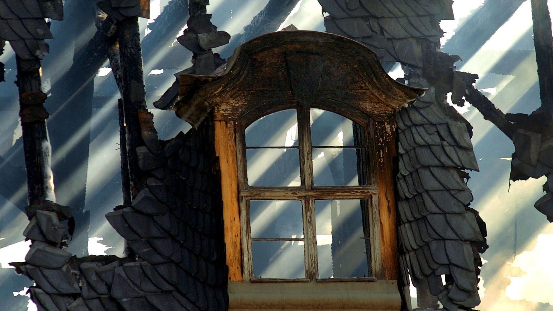 Hinter einem Dachfenster der Anna Amalia Bibliothek in Weimar scheint am 03.09.2004 die Sonne durchs verkohlte Gebälk.