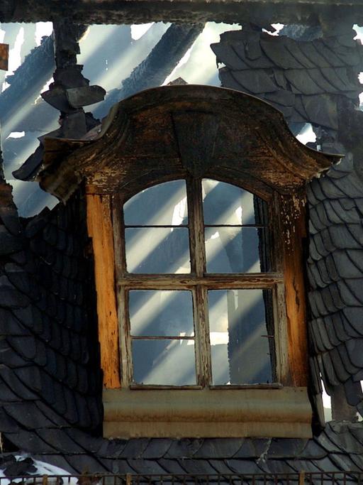Hinter einem Dachfenster der Anna Amalia Bibliothek in Weimar scheint am 03.09.2004 die Sonne durchs verkohlte Gebälk.