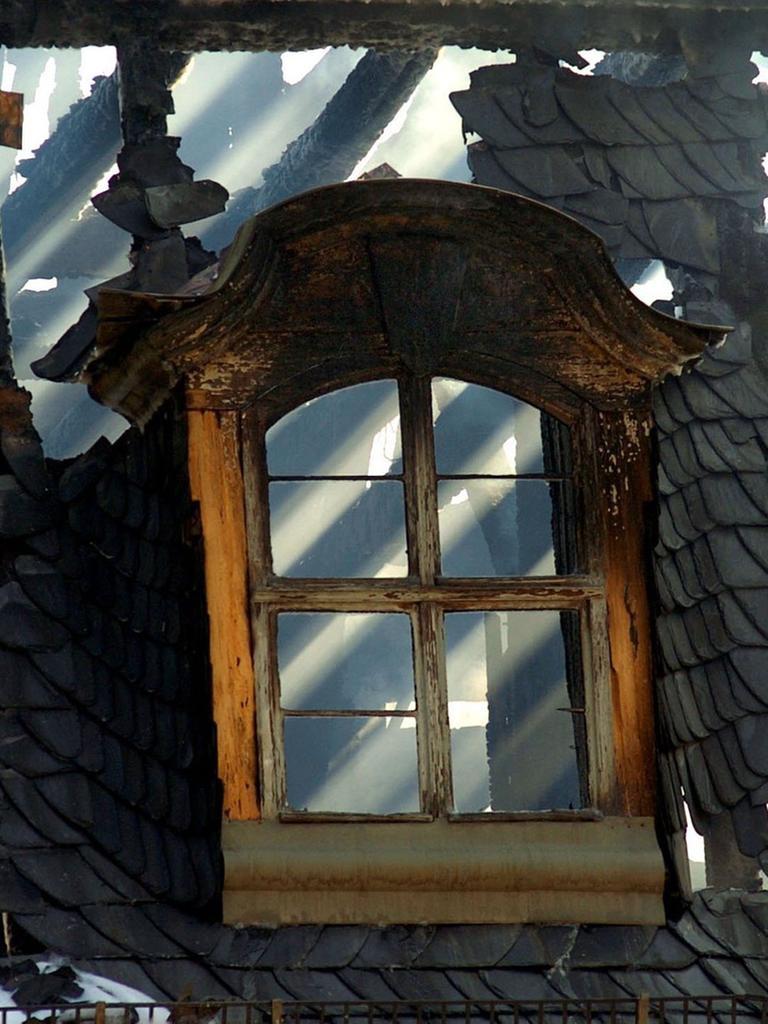 Hinter einem Dachfenster der Anna Amalia Bibliothek in Weimar scheint am 03.09.2004 die Sonne durchs verkohlte Gebälk.