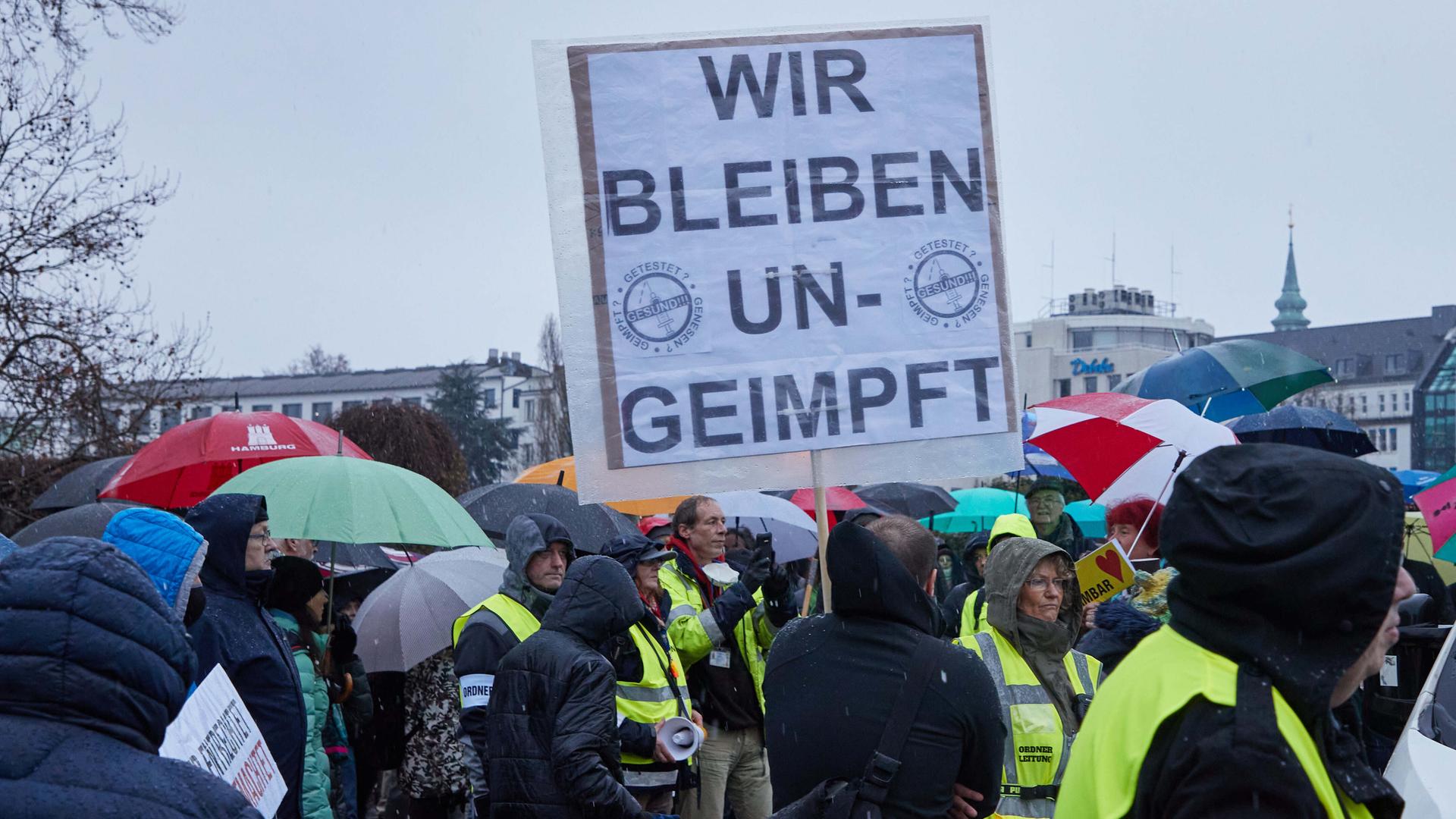 Ein Teilnehmer einer Demonstration von Corona-Impfgegnern hält ein Transparent mit den Aufschrift "Wir bleiben ungeimpft". Ein Teilnehmer einer Demonstration von Corona-Impfgegnern hält ein Transparent mit den Aufschrift "Wir bleiben ungeimpft".