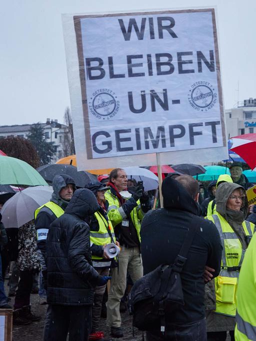 Ein Teilnehmer einer Demonstration von Corona-Impfgegnern hält ein Transparent mit den Aufschrift "Wir bleiben ungeimpft".
