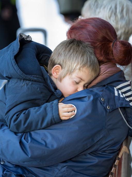  Eine Mutter hält auf dem Berliner Hauptbahnhof ihren schlafenden Sohn auf dem Arm.