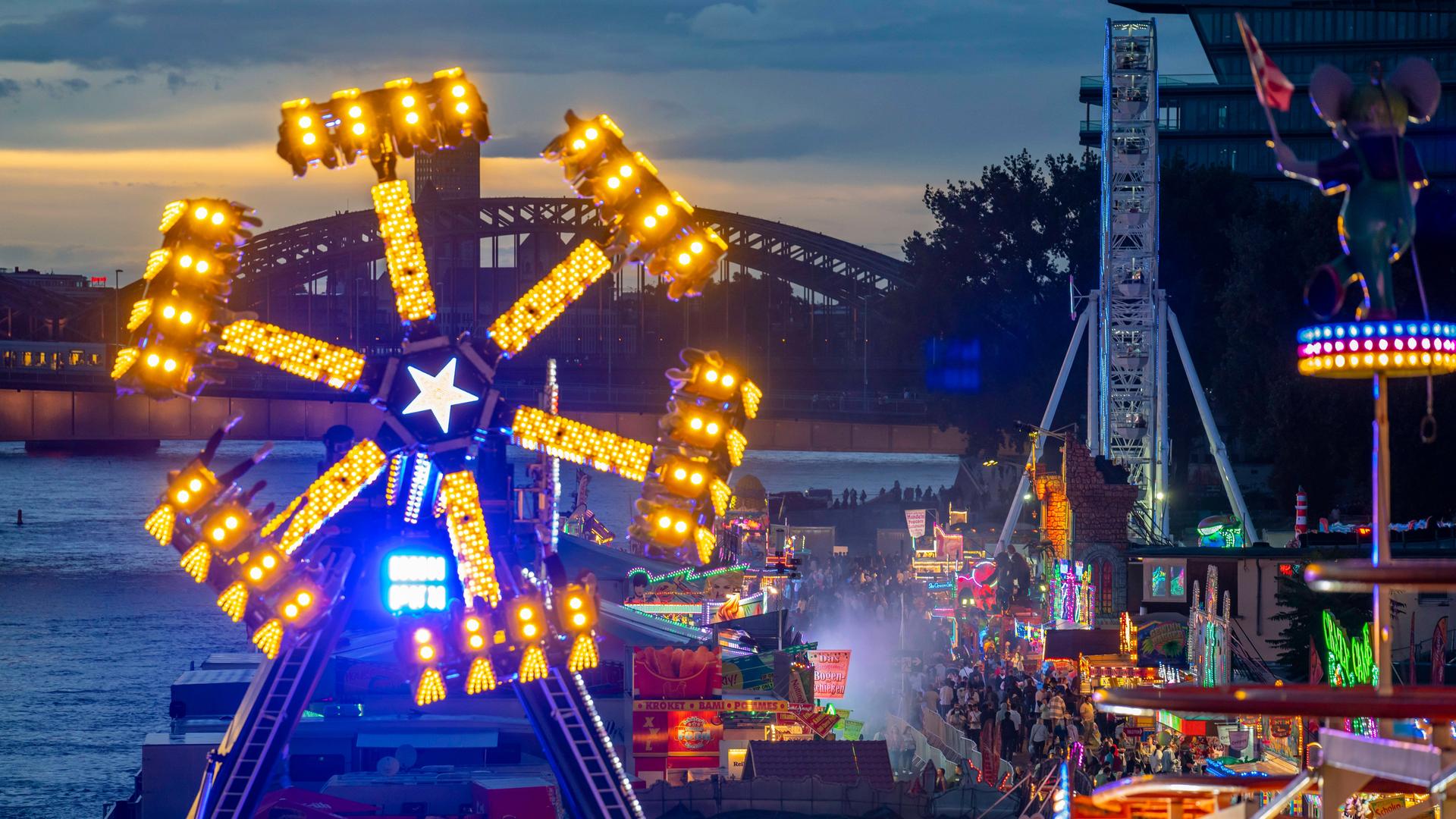 Panoramablick mit abendlicher Stimmung auf die bunt beleuchteten Fahrgeschäfte eines Jahrnarkts am Rhein. Panoramablick mit abendlicher Stimmung auf die bunt beleuchteten Fahrgeschäfte eines Jahrnarkts am Rhein.