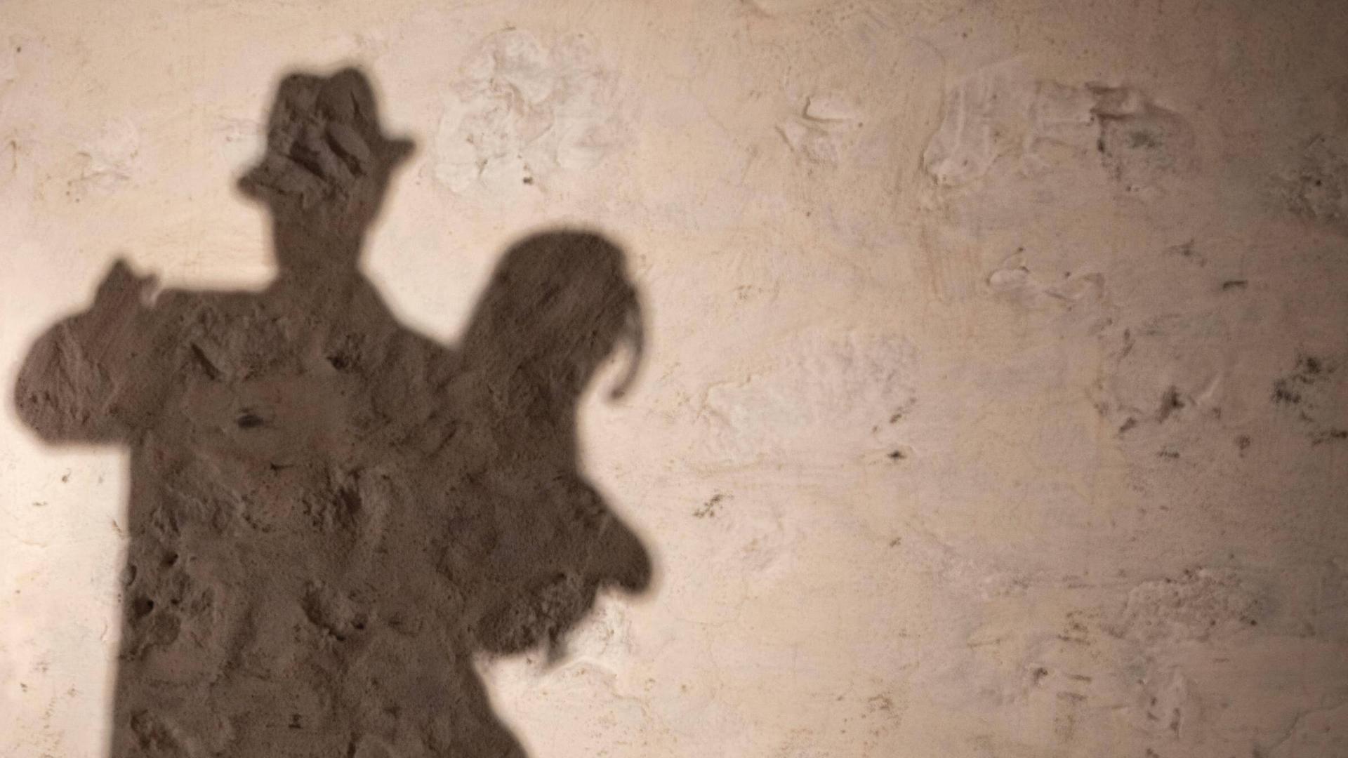 Ein tanzendes Tangopaar wirft seine Schatten auf eine grobe Wand. Ein tanzendes Tangopaar wirft seine Schatten auf eine grobe Wand.