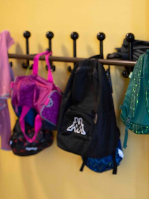 Garderobe mit aufgehängter Kinderkleidung und Taschen in einer Schule.