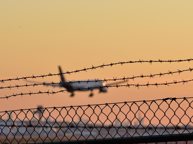 Symbolbild eines Abschiebeflugs. Zu sehen ist ein Flugzeug, das in einen Sonnenuntergang fliegt. 